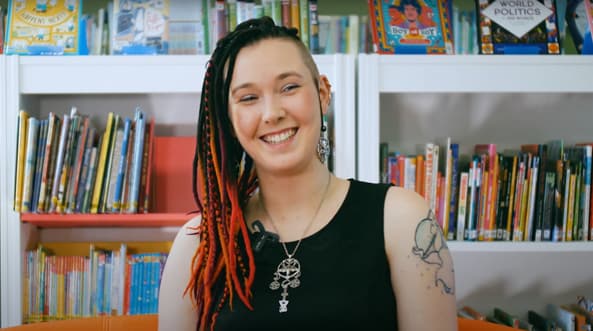 A young woman smiling in front of a bookshelf