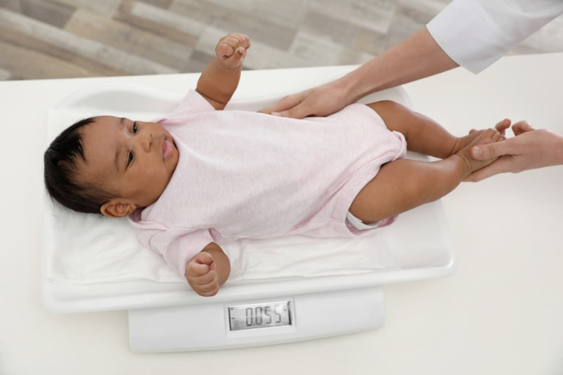 A baby being weighed on a scale.