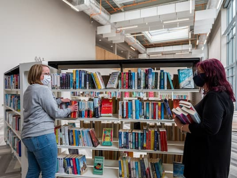 Library staff putting books on a shelf
