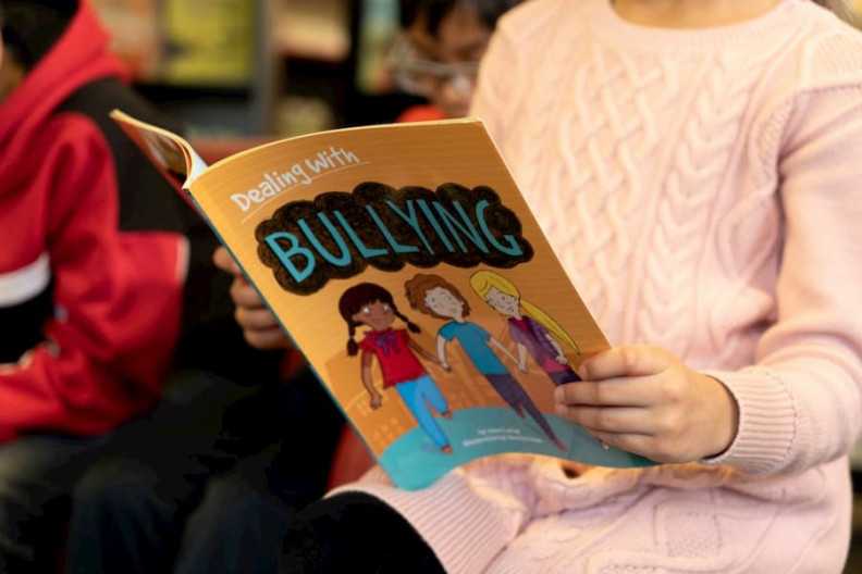 A child reading a book on bullying.