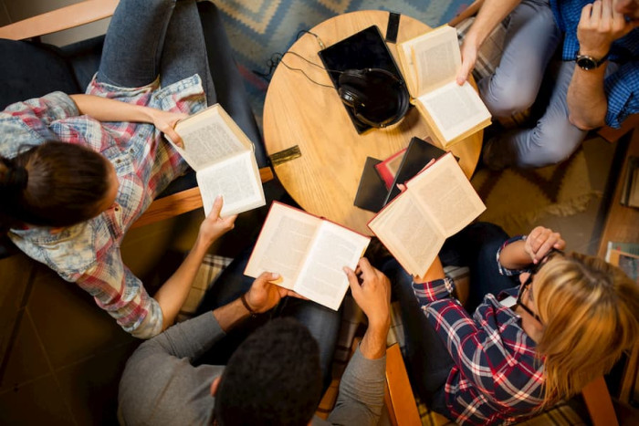 A group of people gathered around a table reading books