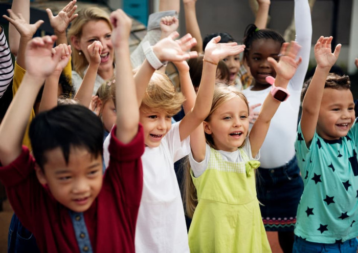Young children smiling with their arms in the air.