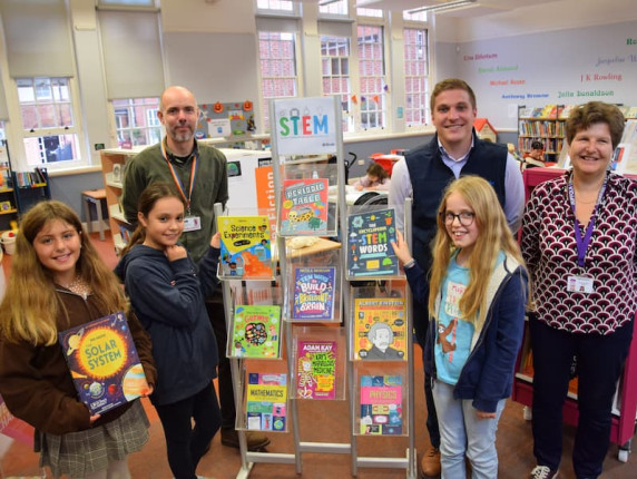 Children standing next to the new STEM bookstand in the library