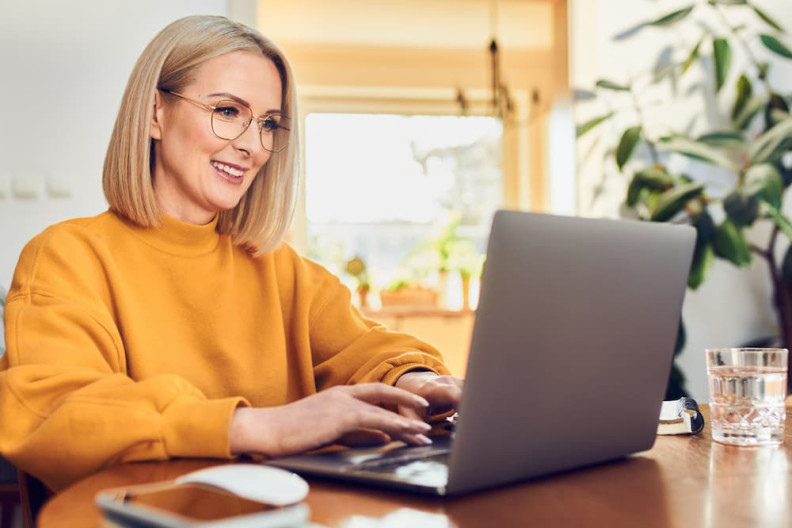 Stock image of a middle aged woman sat on a laptop