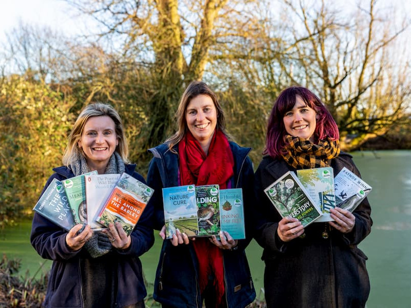 Three women holding copies of our 2021 collection of titles.
