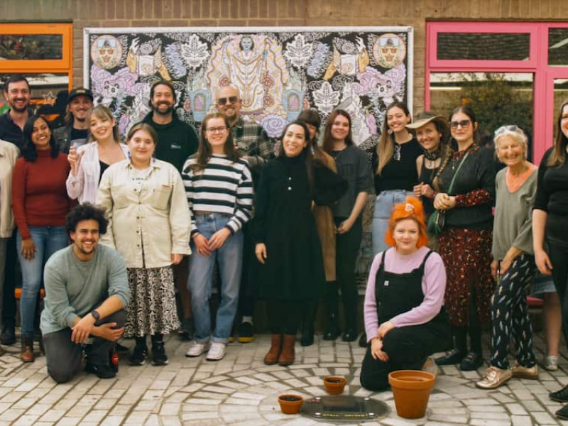 A group of artists in front of a mural in the Stowmarket Library community garden.